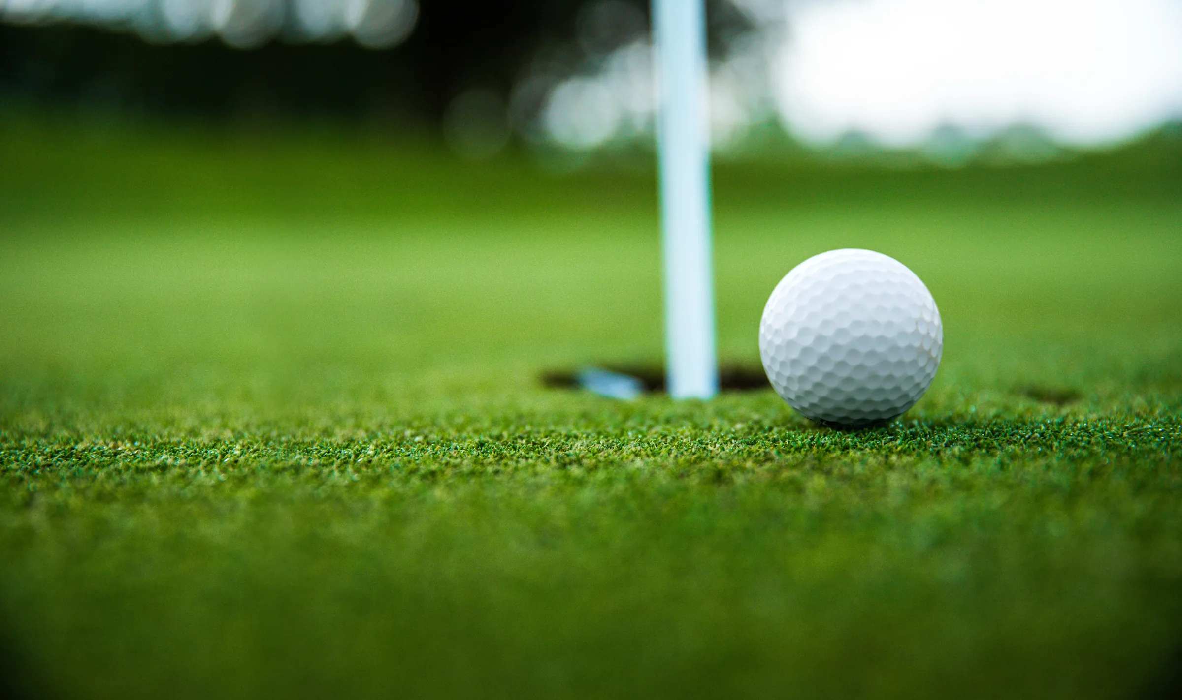 Golf ball beside a hole on a putting green